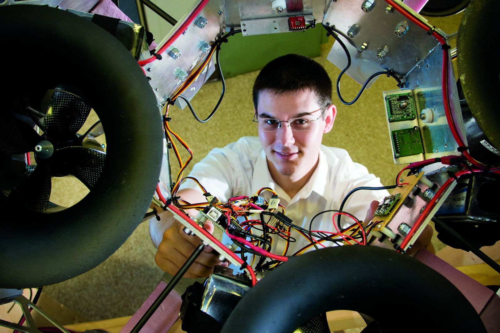 A Lehigh student working on the wiring of a large multi-rotor aircraft frame, seen through the rotor arms