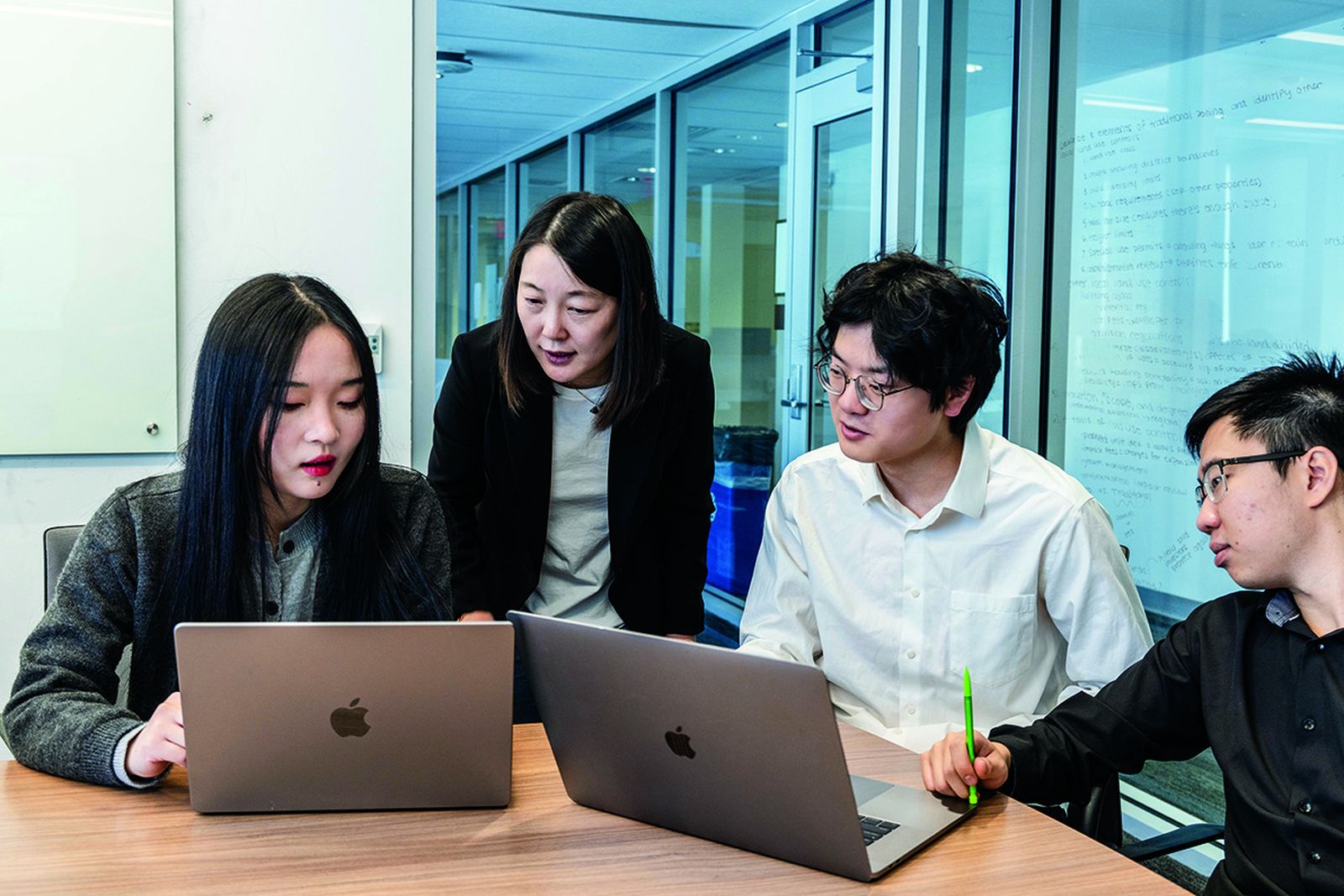 Lifang He working with Lehigh computer science students around laptops in a glass-walled meeting room