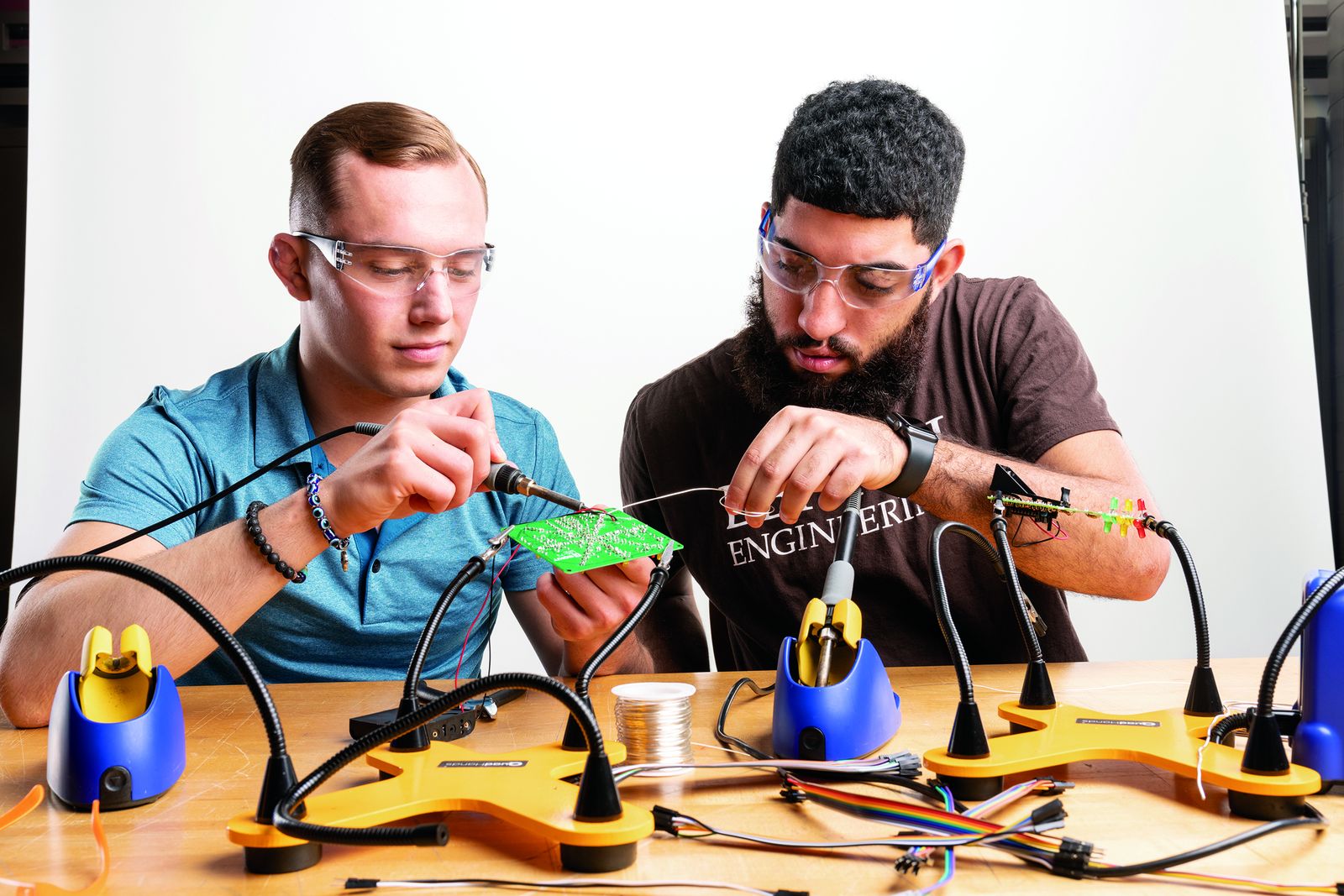 Two Lehigh technical entrepreneurship students soldering a prototype circuit at a workbench