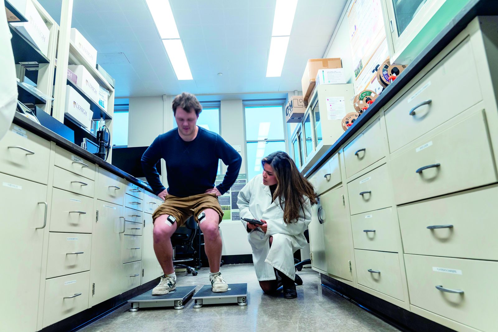 Two Lehigh bioengineering researchers running a gait study, one seated on instrumented equipment while the other records data