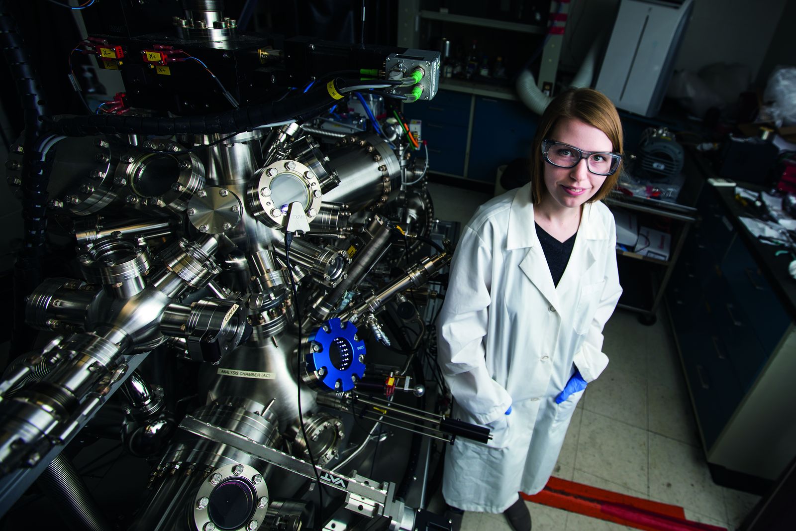 A Lehigh chemical engineering researcher beside a large multi-port vacuum deposition chamber