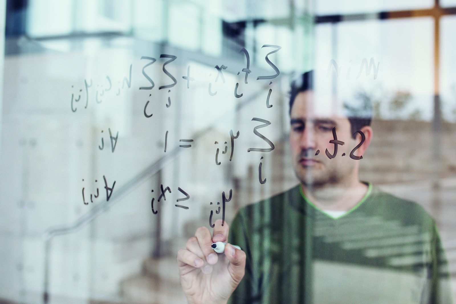 A Lehigh industrial and systems engineering researcher writing equations on a glass board