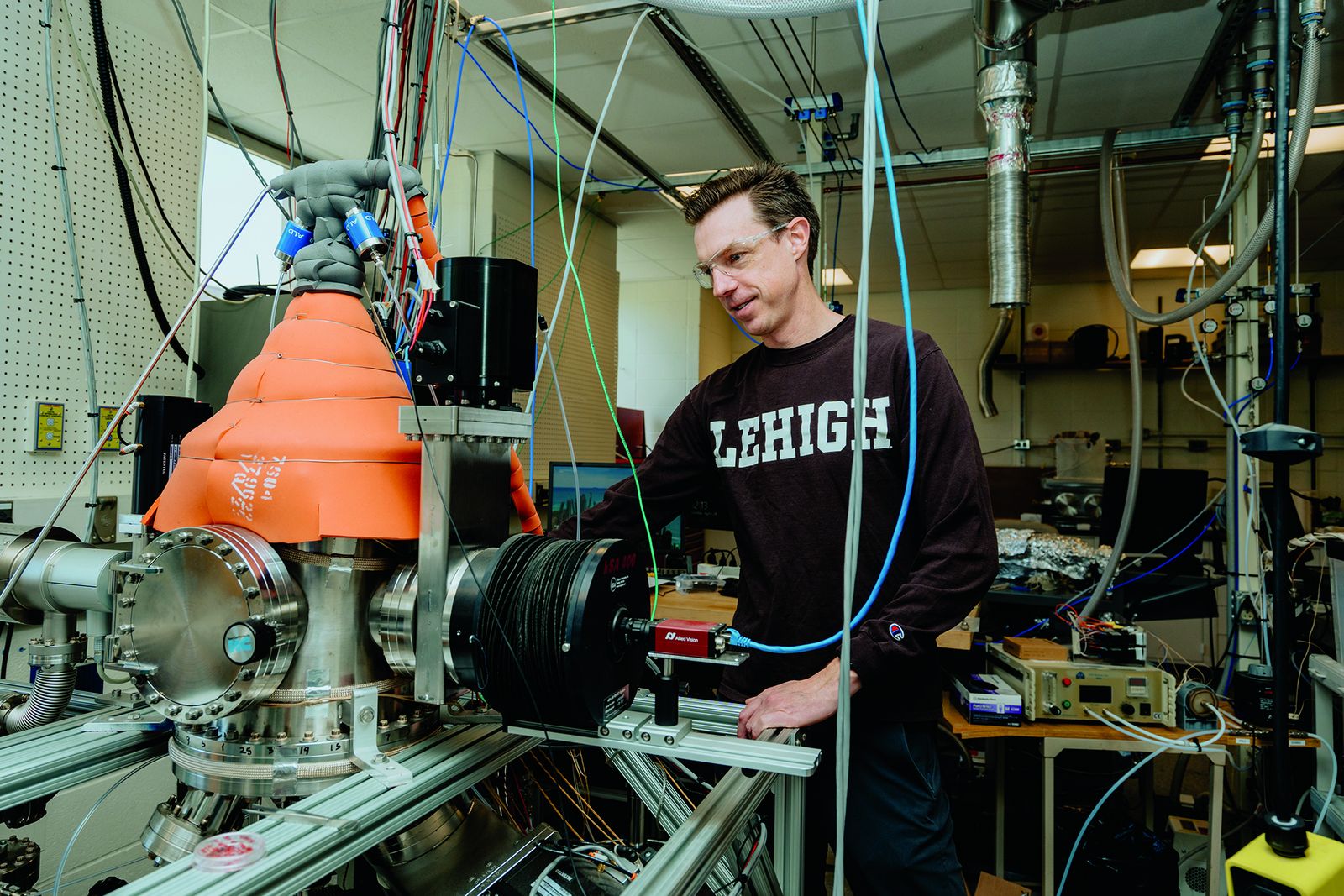 A Lehigh materials science researcher operating a large vacuum deposition system