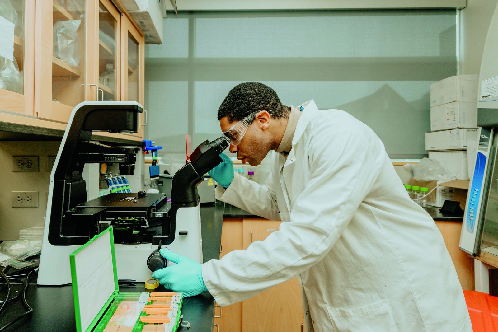 A Lehigh graduate researcher in a lab coat at a microscope