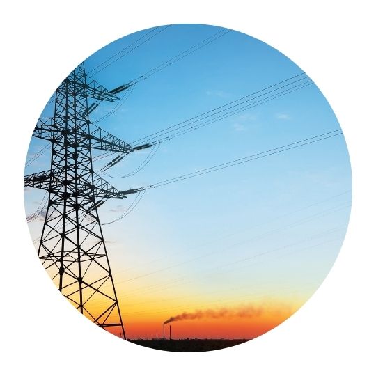 Circular photo of electrical tower at sunset with smokestack in the distance