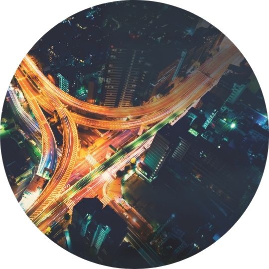 Circular aerial photo of urban highway interchange at night with bright lights