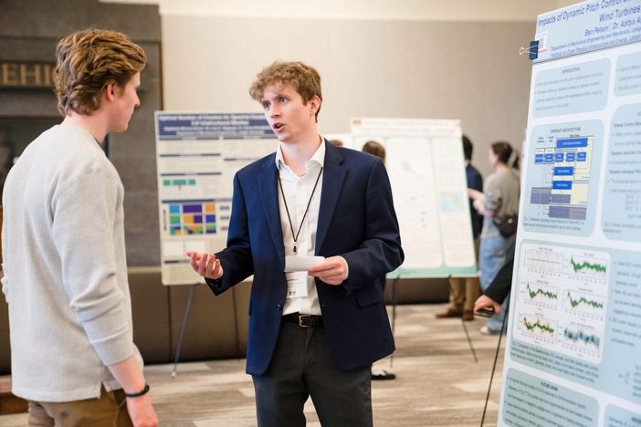 Two students discuss a poster at the 2025 UGRS