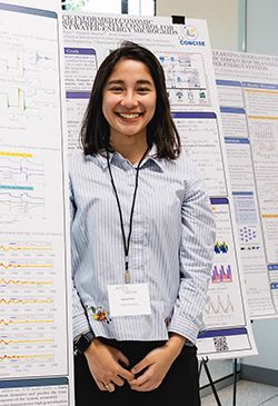 Saskia Putri stands in front of research posters