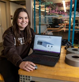 Hannah Peik with laptop and elements of Mars Rover project