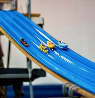 Student built and designed mini race cars go down the track