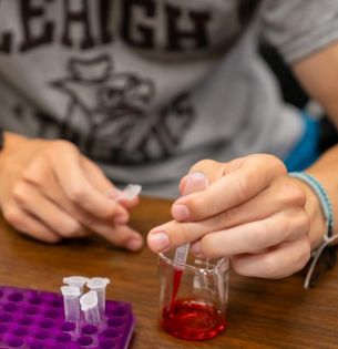 Detail image of student hands working with beaker for Purple Drop