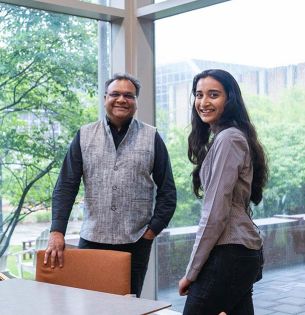 Khanjan Mehta (left) and Vrushti Patel ’26 stand beside a conference table in a room with large windows overlooking campus.