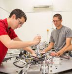 Ph.D. candidates Zachary Farley (left) and Andrew Bergey set up a test on a two-wheel, high-acceleration track, which simulates the instabilities of the fusion reactor by rotating a container filled with two fluids of different densities.