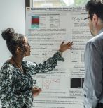Student presenting research poster to faculty member