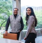 Khanjan Mehta (left) and Vrushti Patel ’26 stand beside a conference table in a room with large windows overlooking campus.