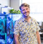 Patrick Clasen standing next to an aquarium 