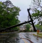 telephone pole down in road after storm