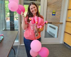 Photo of a smiling Chayah Wilbers holding plastic flamingos and pink balloons