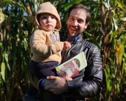 Photo of Dominic DiFranzo and his child in corn field, smiling at the camera